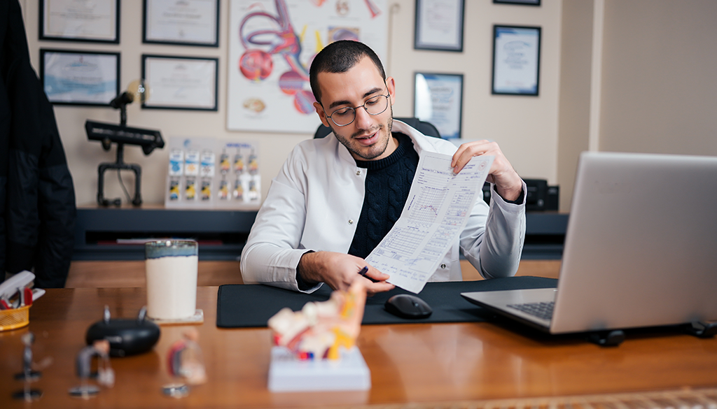 physician sitting at desk with papers