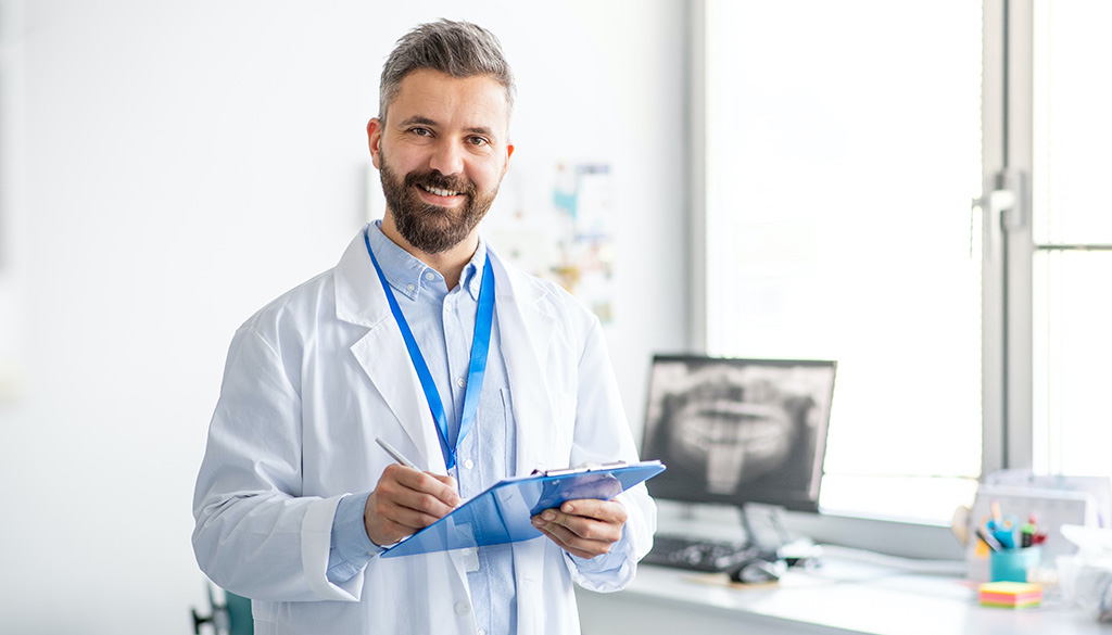 dentist with clipboard in front of xray of teeth