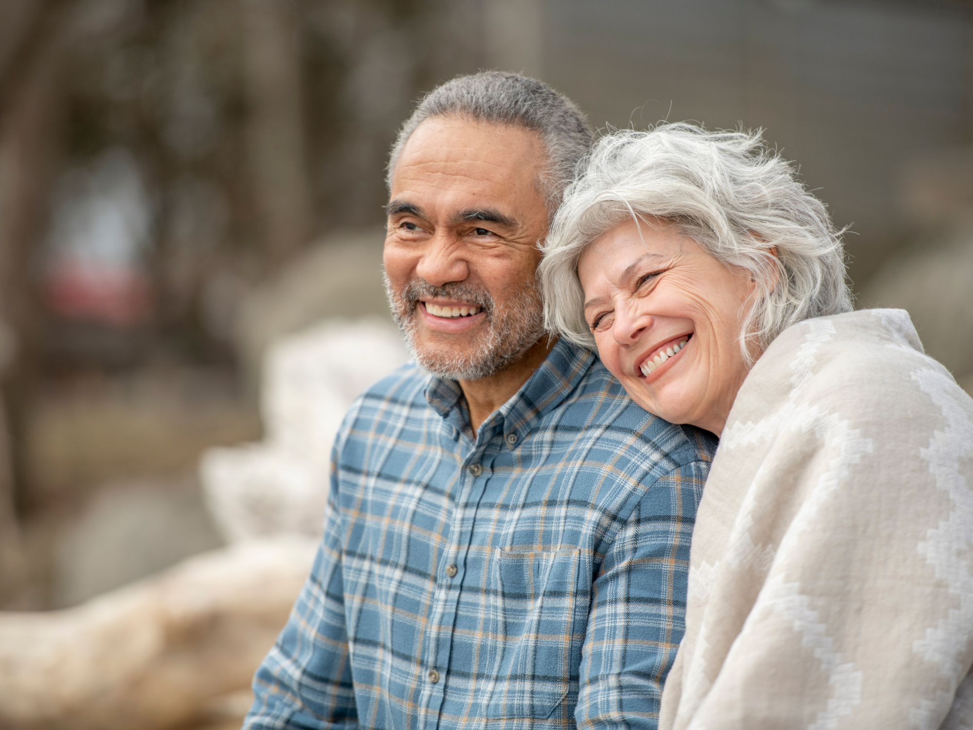 a smiling older man and woman sitting outside