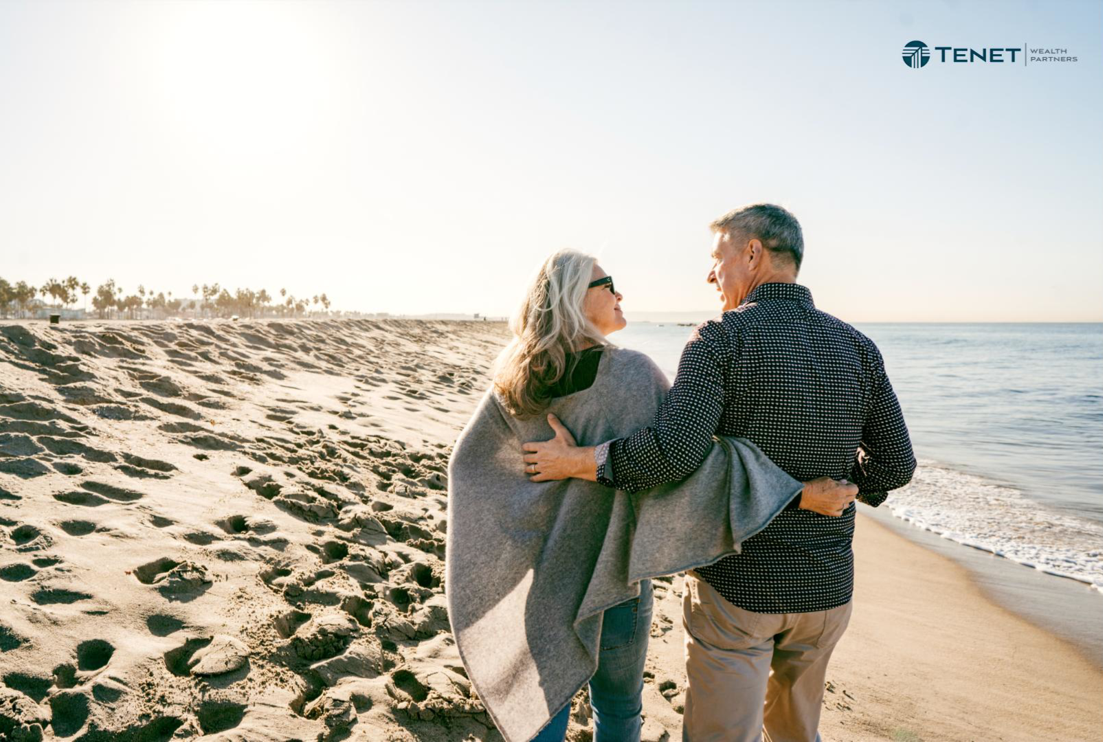 happy retired couple walking on the beach together